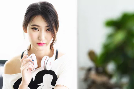 HD desktop wallpaper featuring an Asian brunette woman with brown eyes wearing white headphones, posing confidently against a bright, blurred background.