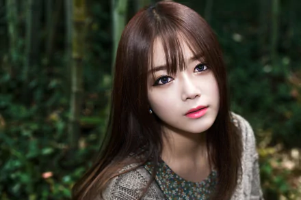 A brunette woman with striking purple eyes gazes thoughtfully at the camera, set against a lush green background, creating a captivating HD wallpaper.