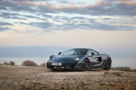 McLaren 570GT supercar parked on coastal scrub overlooking the sea and pastel sky — 4K Ultra HD PC desktop wallpaper of a sleek McLaren vehicle