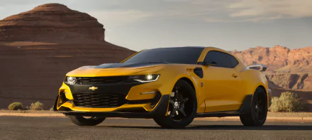 A HD desktop wallpaper of a yellow Camaro from the movie Transformers: The Last Knight, set against a scenic desert backdrop.