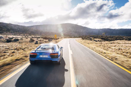 Blue Audi R8 V10 supercar driving on an open road with mountains in the background, captured as a 4K Ultra HD PC desktop wallpaper.