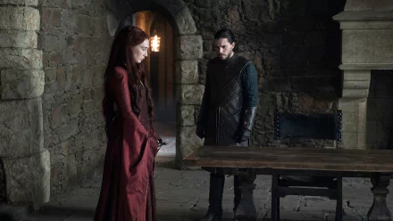 Melisandre and Jon Snow, characters from Game of Thrones played by Carice van Houten and Kit Harington, stand in a dim stone chamber in this HD PC desktop wallpaper.