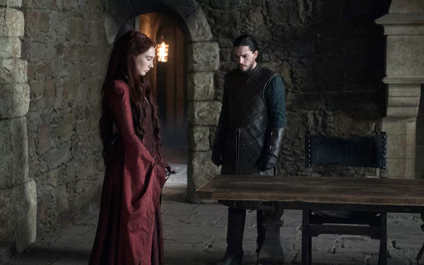Melisandre and Jon Snow, characters from Game of Thrones played by Carice van Houten and Kit Harington, stand in a dim stone chamber in this HD PC desktop wallpaper.