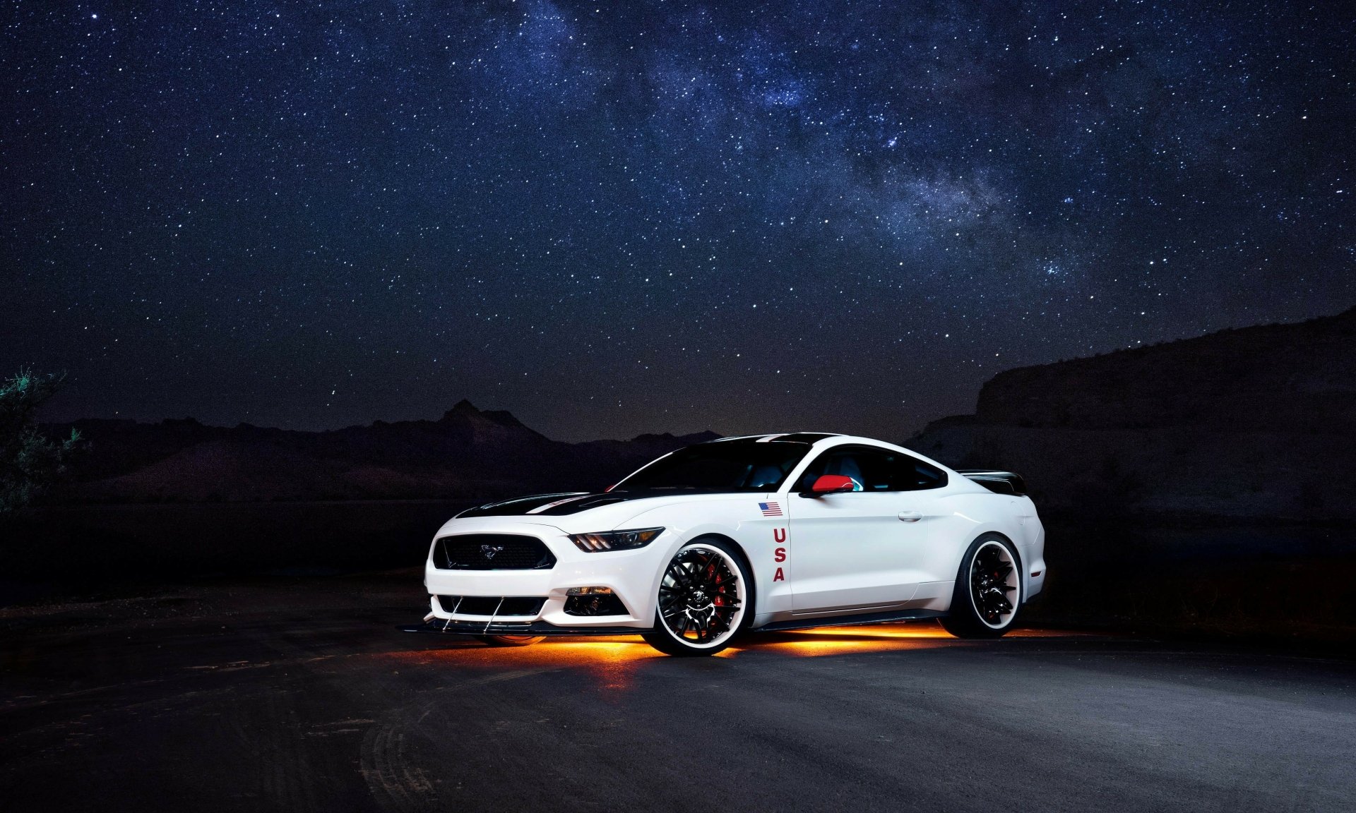 A white Ford Mustang with glowing orange underglow lights parked under a star-filled night sky, captured in 4K Ultra HD for a PC desktop background.