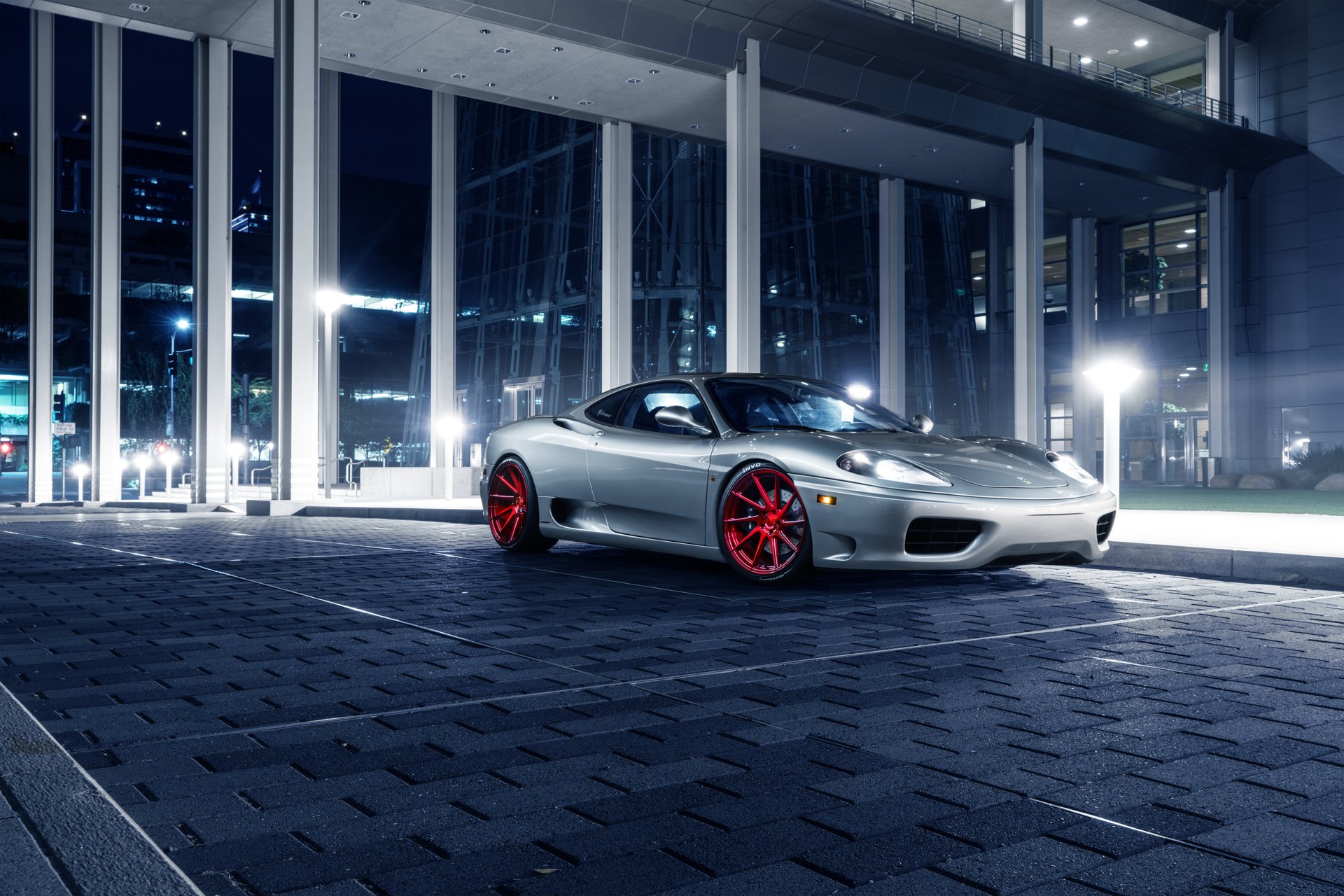 Silver Ferrari 360 Modena supercar with red wheels parked in a modern urban setting at night, captured in high-definition for PC desktop wallpaper.