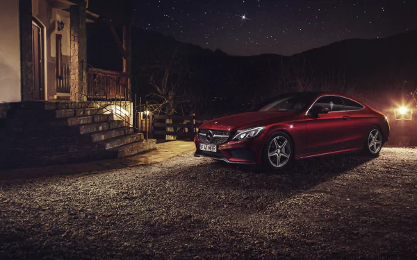 A red Mercedes-Benz C-Class parked outside a house at night under a starry sky, captured in stunning 4K Ultra HD as a sleek vehicle wallpaper.