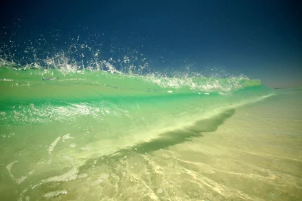 HD desktop wallpaper and background image featuring a stunning natural wave, captured mid-motion, with clear, vibrant water under a bright blue sky.
