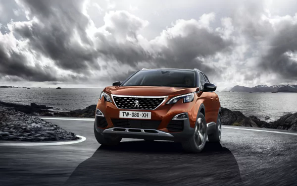 Orange Peugeot 3008 SUV driving on a coastal road with dramatic cloudy sky, captured in high-definition for a PC desktop wallpaper.