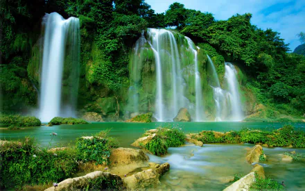 Majestic Ban Gioc-Detian Falls cascades through lush greenery in Vietnam, creating a stunning natural landscape. A vibrant HD wallpaper showcasing the beauty of nature.