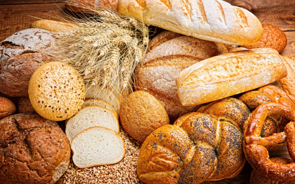 4K Ultra HD PC desktop wallpaper featuring a variety of freshly baked breads and wheat stalks, showcasing rich textures and warm tones in a baking-themed food composition.