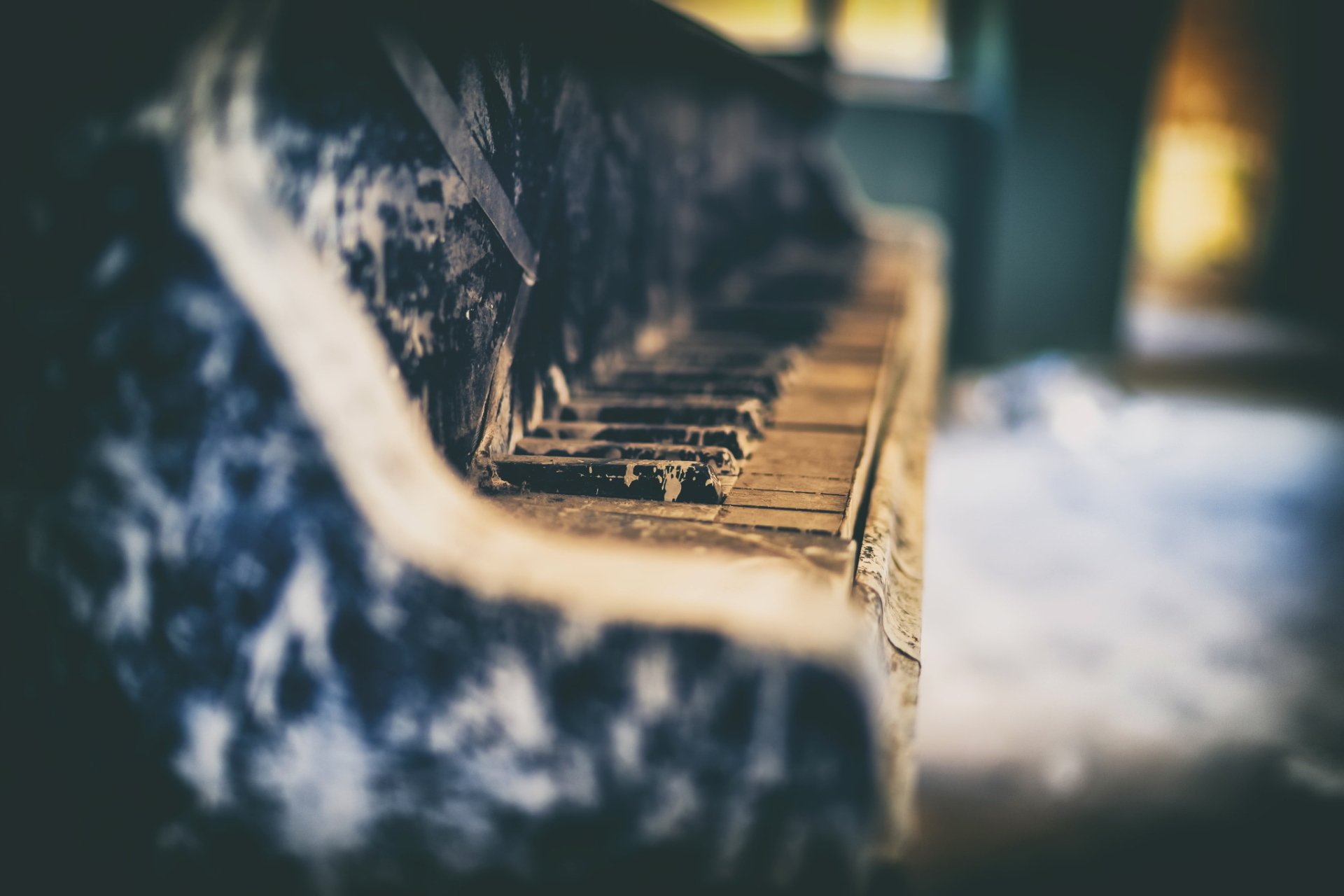 HD PC desktop wallpaper of a dust-covered, worn piano keyboard; close-up instrument shot with soft-focus background evoking faded music and vintage atmosphere.