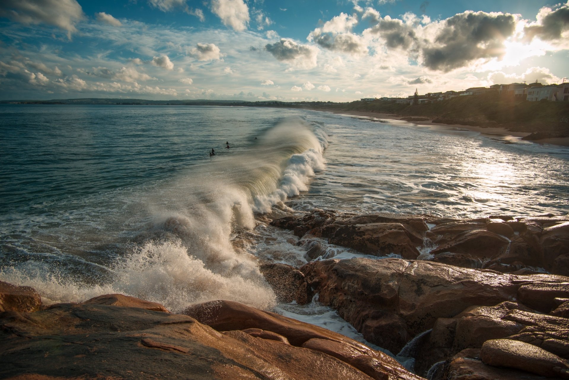 HD desktop wallpaper of powerful ocean waves crashing along the rocky Australian coastline under a vibrant sky, showcasing the dynamic beauty of sea and earth.