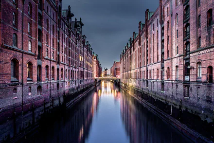 A nighttime view of Hamburg's iconic canal flanked by historic red brick buildings, showcasing the city's man-made urban architecture in Germany.