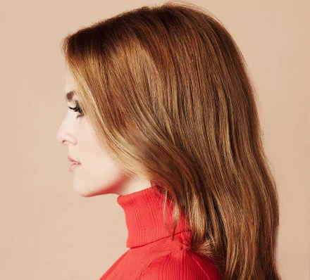 Side profile of American brunette actress Zoey Deutch with sleek hair and wearing a red turtleneck, captured in a high-definition desktop wallpaper.