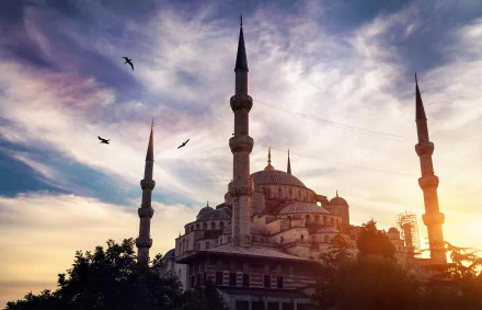 HD PC desktop wallpaper featuring the Sultan Ahmed Mosque with its minarets silhouetted against a dramatic sunset sky, capturing the mosque's religious and architectural grandeur.