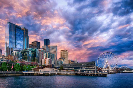 HD desktop wallpaper showing Seattle's cityscape with skyscrapers, the iconic Ferris wheel, and vibrant cloud-filled sky over the waterfront in the USA.