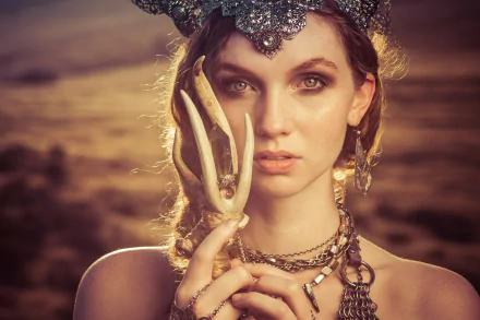 A close-up of a redheaded woman with green eyes, adorned in intricate jewelry and a striking necklace, holding an antler. She embodies a captivating cosplay aesthetic.