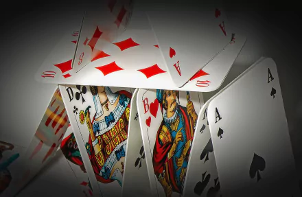 A collection of playing cards arranged in a house of cards design, featuring vibrant illustrations, captured in a high-definition desktop wallpaper and background.