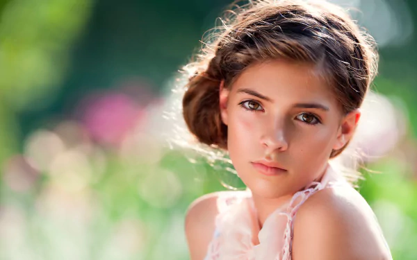 A woman gazes thoughtfully, framed by a soft bokeh background of colorful blooms, creating a serene and captivating HD wallpaper for desktop use.