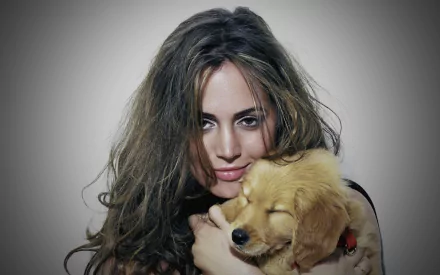HD desktop wallpaper featuring celebrity Eliza Dushku with tousled hair, gently holding a golden retriever puppy against a soft gray background.