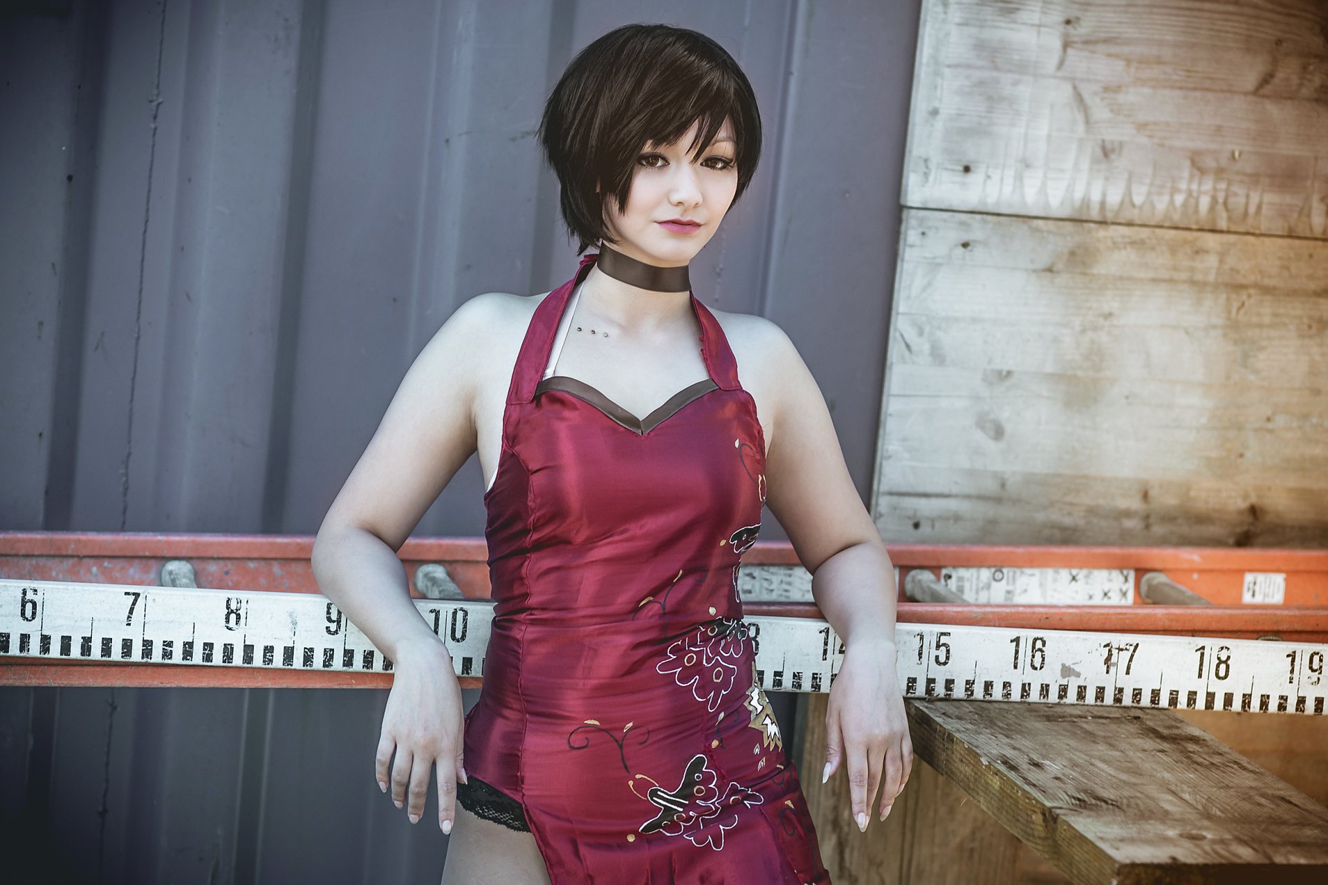 A woman with short black hair poses in a red dress, embodying Ada Wong from Resident Evil. The HD image serves as a vibrant desktop wallpaper or background.