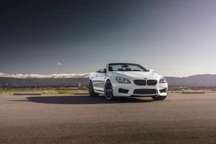White BMW M6 Cabriolet parked on a wide open road with mountains in the background, featured in an HD desktop wallpaper.