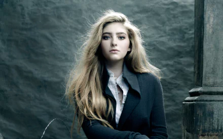 HD desktop wallpaper of American actress Willow Shields with long blonde hair, wearing a dark coat against a textured, moody background.
