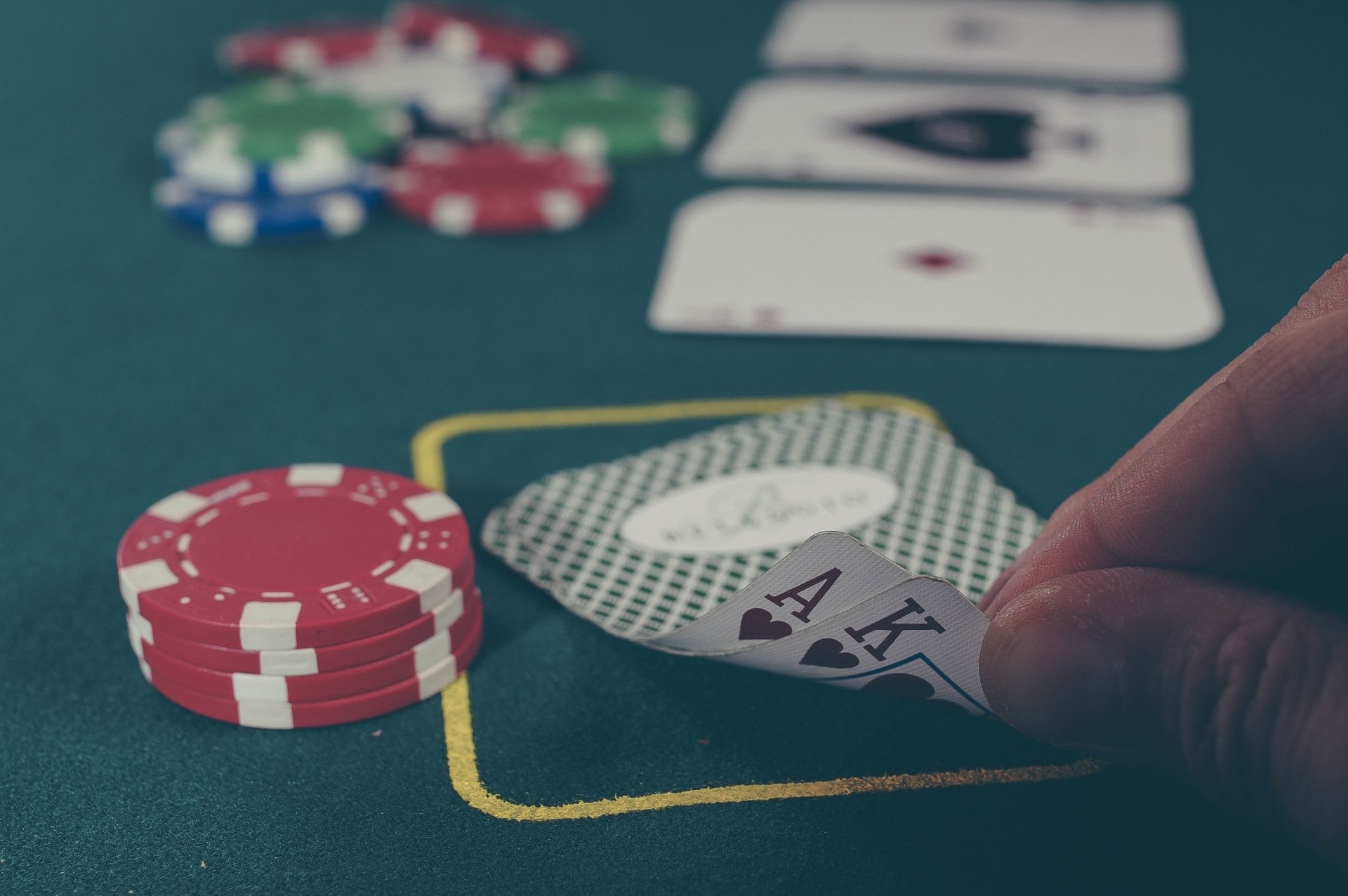 A close-up of a poker hand being revealed on a green felt table, with red poker chips nearby, captured in 4K Ultra HD for a PC desktop background.