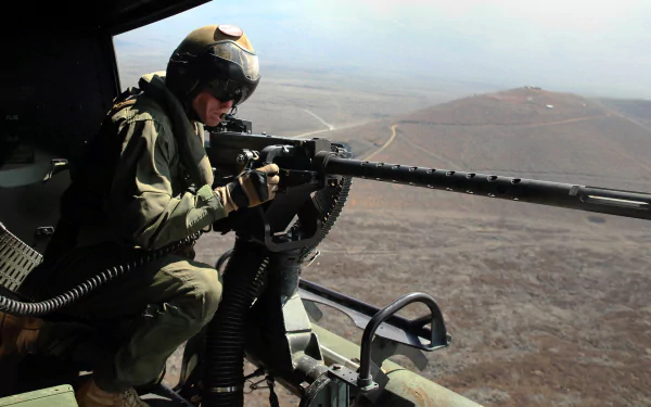 A soldier in military gear aims a machine gun from a helicopter, overlooking a rugged landscape, captured in vibrant 4K Ultra HD detail.