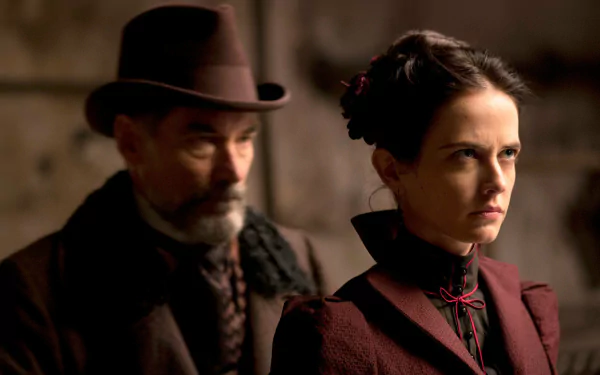 A dramatic scene from the TV show Penny Dreadful, featuring a stern woman in Victorian attire with a serious expression, as a man in a hat looms closely behind her.