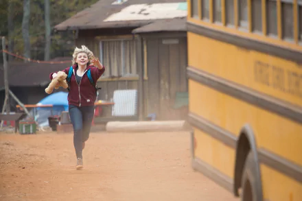 Chloë Grace Moretz running with a teddy bear near a yellow school bus in a scene from the movie The 5th Wave, rendered as a 4K Ultra HD PC desktop wallpaper.