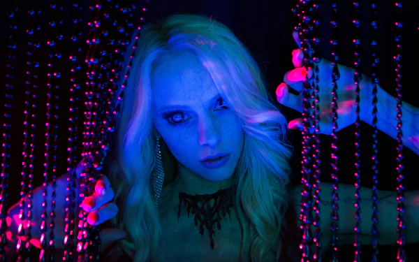 Blonde woman amid hanging beads, bathed in neon blue and magenta light — 5K Ultra HD PC desktop wallpaper depicting a scene from the movie Scouts Guide to the Zombie Apocalypse