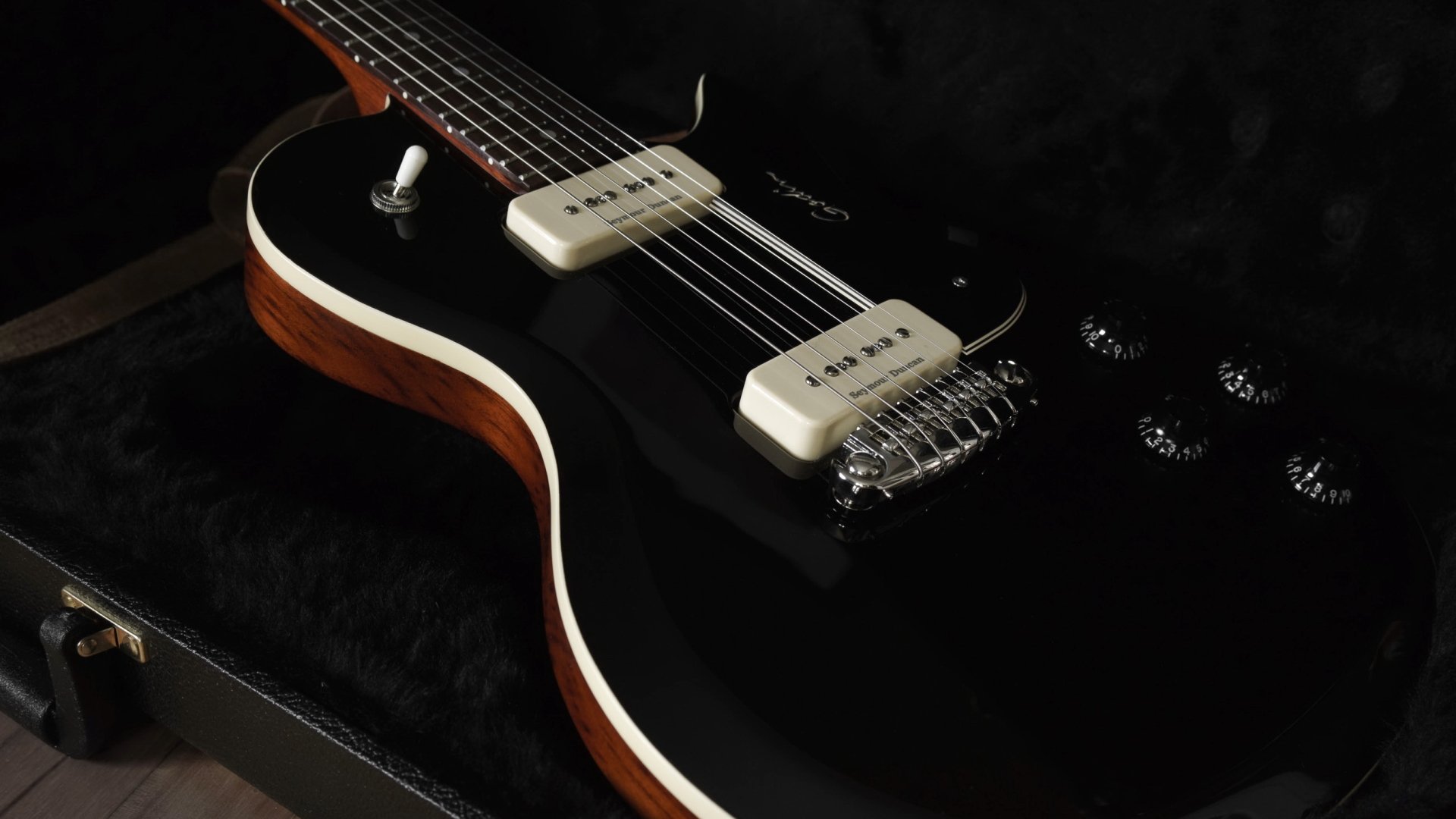 Close-up of a black electric guitar showing white pickups, strings and wood edges; music instrument 2K Quad HD PC desktop wallpaper background.
