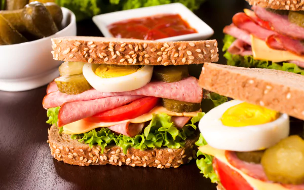 4K Ultra HD image of a fresh sandwich with sesame seed bread, layered with boiled egg, lettuce, pickles, and sliced deli meat, set against a dark background.