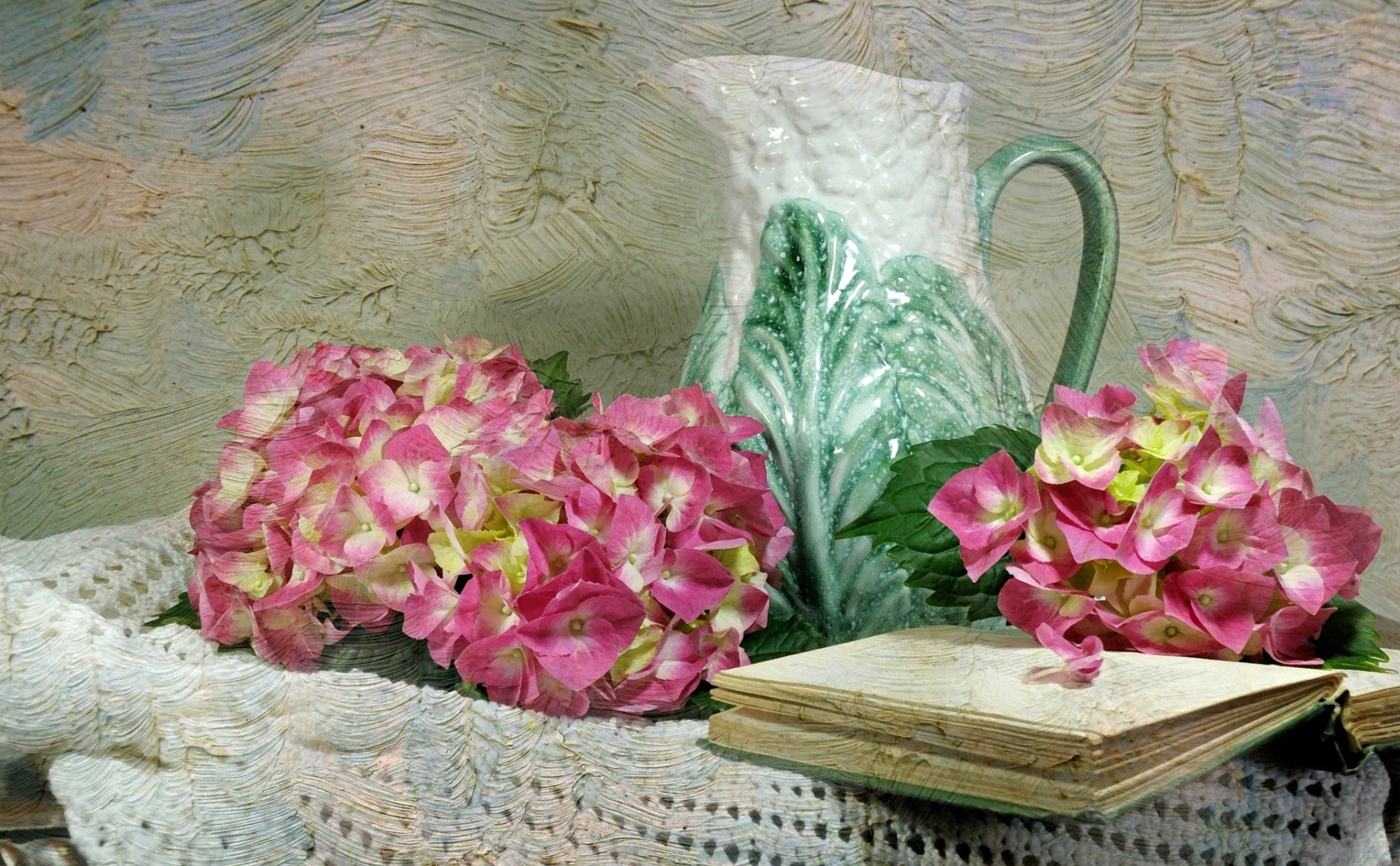 A still life composition featuring pink hydrangea flowers beside a vintage pitcher and an open book, all set on a textured background, creating a tranquil and inviting scene.
