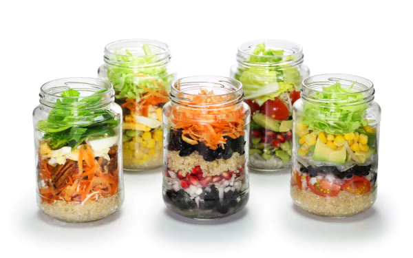 A vibrant 4K Ultra HD desktop wallpaper featuring jars filled with layered salad ingredients like beans, corn, lettuce, pomegranate, cucumber, nuts, carrot, and tomato.