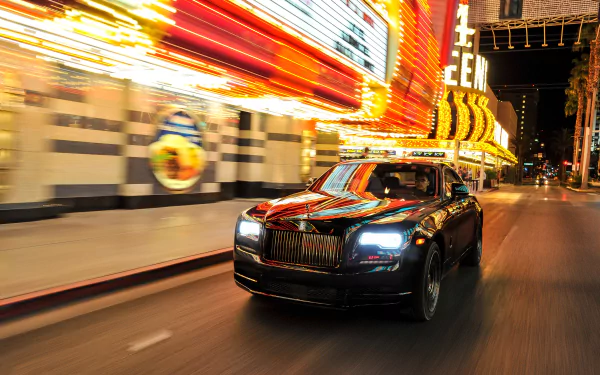 A black Rolls-Royce Wraith driving through a brightly lit city street at night, captured in 4K Ultra HD for a PC desktop wallpaper.