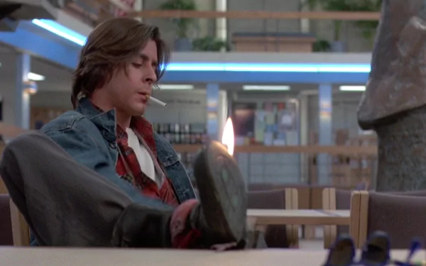 HD desktop wallpaper featuring Judd Nelson as John Bender from the movie The Breakfast Club, seated in the school library with a defiant expression.