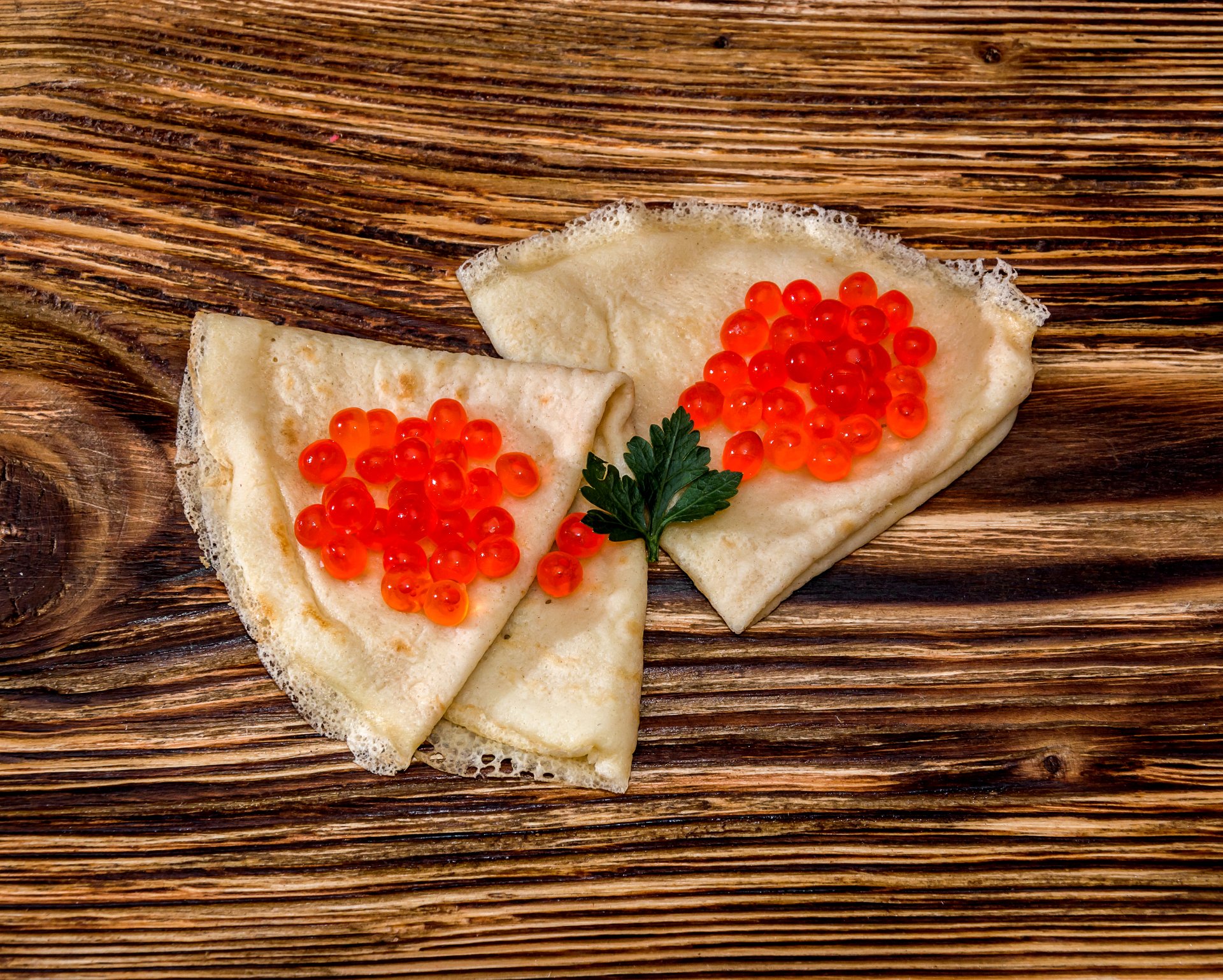 4K Ultra HD PC desktop wallpaper/background: two folded crêpes topped with bright red caviar on a rustic wooden board, food photography.