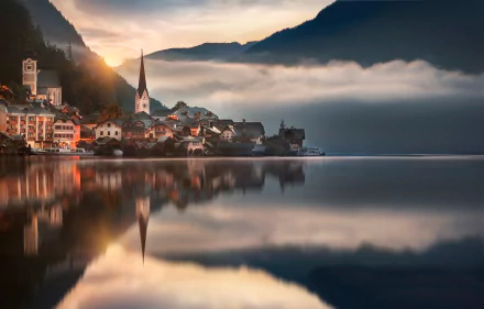 A serene view of Hallstatt, Austria, showcasing a lake reflecting the village against a backdrop of clouds and mountains, captured in stunning HD quality.