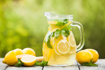 A refreshing pitcher of lemon-infused drink with mint, surrounded by fresh lemons. A bright and vibrant 4K Ultra HD wallpaper showcasing an enticing beverage.