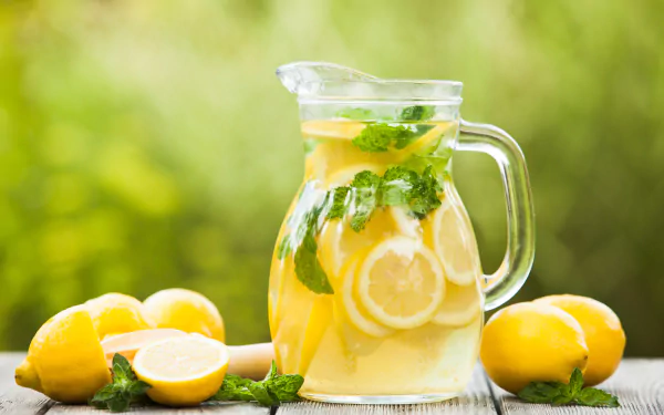 A refreshing pitcher of lemon-infused drink with mint, surrounded by fresh lemons. A bright and vibrant 4K Ultra HD wallpaper showcasing an enticing beverage.
