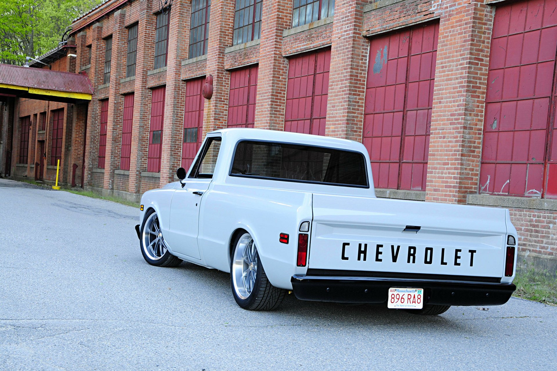 White 1972 Chevrolet C10 hot rod parked beside a brick industrial building, showcased as an HD PC desktop wallpaper and background.