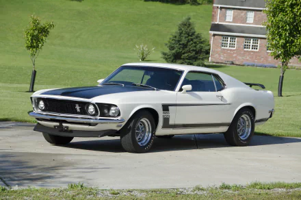 1969 white Ford Mustang Boss 302 muscle car parked on pavement with green lawn and brick building in the background, HD desktop wallpaper.