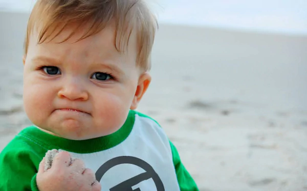 A curious child at the beach in a green shirt, posing for a crisp HD desktop wallpaper.