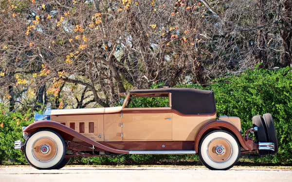 Tan-and-brown 1931 Packard Deluxe Eight Convertible Victoria vintage car, side view against autumn foliage — HD PC desktop wallpaper background.