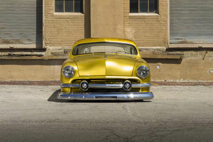 A vibrant yellow 1951 Ford Custom lowrider hot rod parked in front of a beige brick building, captured as an HD PC desktop wallpaper and background.
