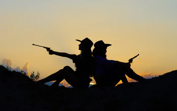 Silhouette of two cowgirls sitting back-to-back, each holding a gun, against a vibrant sunset. A striking HD wallpaper capturing strength and camaraderie.