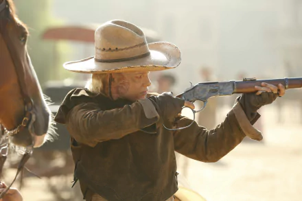 A character from Westworld aims a rifle while wearing a cowboy hat, evoking the show's themes of the Wild West. The image features Ingrid Bolsø Berdal in a dynamic pose.