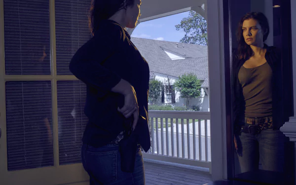 2K Quad HD PC wallpaper of a tense doorway scene from The Walking Dead: a woman inside confronts another on the porch, moody lighting with a suburban house visible outside.